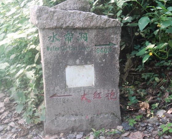 a stone sign appoiting to the right up to Water Curtain Cave and the left down to Da Hong Pao.