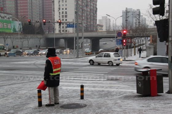 A dutiful warden is standing at his post guiding the traffic.
