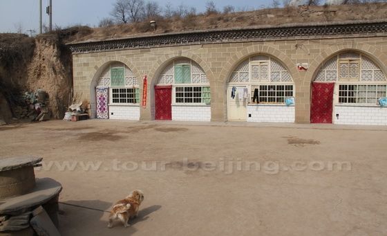 A stone cave dwelling coutyard with a dog gate keeper