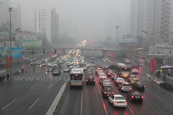 All the buses and cars are driving in the foggy and gloomy day.