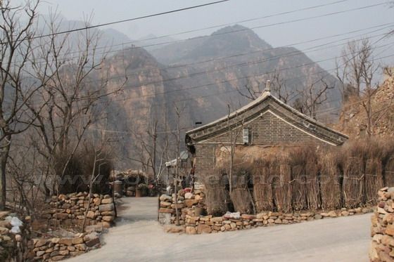 An old house with 2 or 3 rooms within a shabby stone wall, forming a simple courtyard.