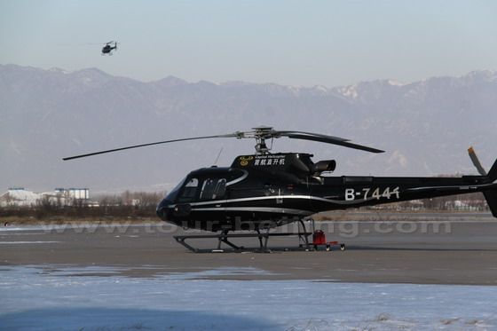 One helicopter is flying and the other is waiting for the instruction.