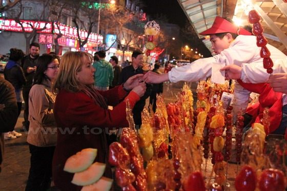 The lady has bought a stick of Tanghulu.
