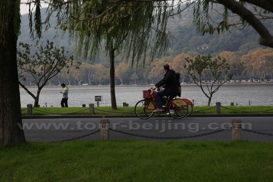 Two foreign visitors are cycling on the Baidi Causeway