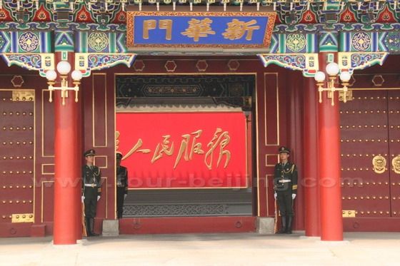 Two soldiers standing by the Xinhuamen Gate. The view inside is blocked by a wall with the sologan - Serve the People.
