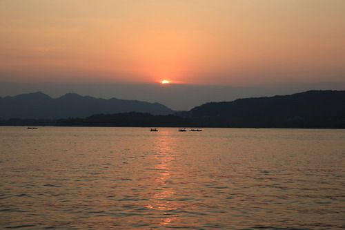The boats are cruising on the reddish surface of the lake